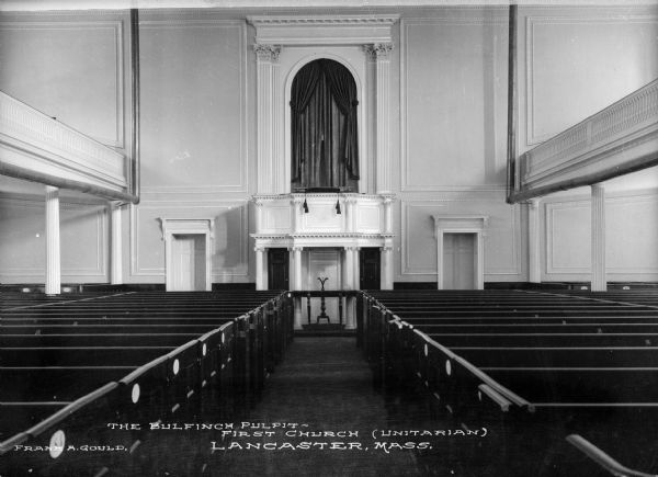 An interior view of First Church showing the pews, pulpit, and upper balcony, which runs the length of both sides. The pulpit has a door flanking each side. Caption reads: "The Bulfinch Pulpit-First Church (Unitarian) Lancaster, Mass."