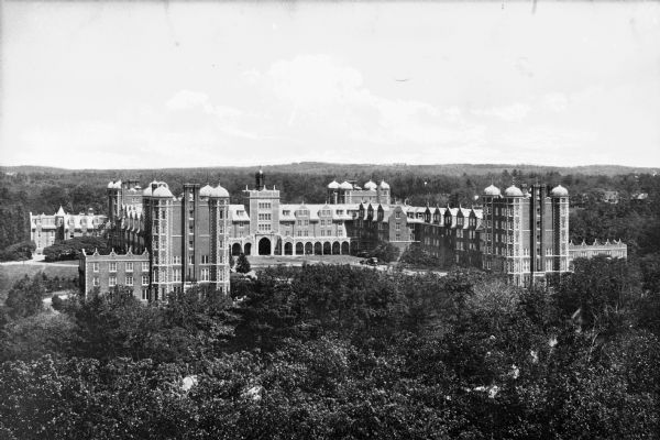 A view of the Quadrangle at Wellesley College, taken from an elevated  vantage point. Large brick and stone buildings surround the area, and each corner has a series of four towers.