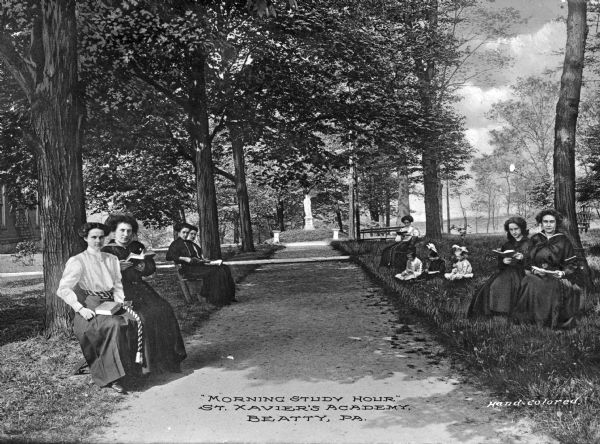 View depicting the "morning study hour," taking place outdoors at St. Xavier's Academy. Women and children sit on benches and in the grass on either side of a pathway leading to a statue in the distance. Caption reads: "'Morning Study Hour' St. Xavier's Academy. Beatty, PA."