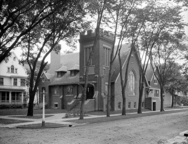 View across street toward the front and left side of the First Congregational Church. Its main entrance is part of the belfry structure. There is a large stained glass window facing the street.