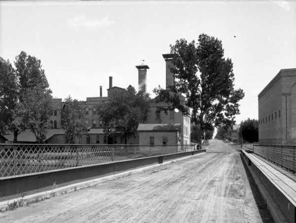A view of the back of the brewery, taken from a bridge.  A man walks across the bridge, away from the camera.