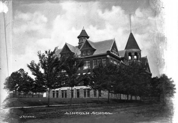 View toward front and right side of the Lincoln School, partially obscured by trees. The roof line features dormers and two towers. Caption reads: "Lincoln School."