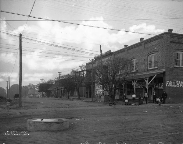 View across street toward commercial buildings. Signs read: "Post Office" "First National Bank" and "J.E. Toole's."
