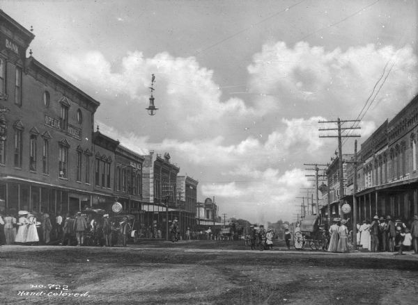 Walnut Street lined with storefronts, horse-drawn carts and pedestrians. Electric lights hang over the street. Signs on buildings read: "Opera House" and "Golden Rule."