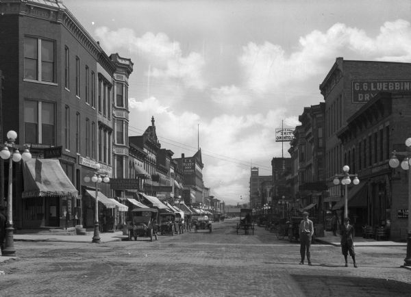 Galena Street business district. Business signs read: "J.D. Wheat Department Store," "Lilley & Foss Clothiers 124 Galena St.," "Kimball Pianos," "E.A. Blust Dry Goods," "Central Dry Goods Store" and "Hardware Stoves and Furnaces."