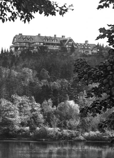 View of "The Eyrie," summer home of American industrialist John D. Rockefeller, overlooking a river from the top of a hill. The home was erected in 1914 and demolished in 1962.