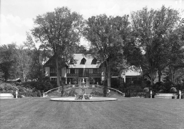View of "Brookside" residence featuring outside staircases, sculptures, fountain and a vast lawn.