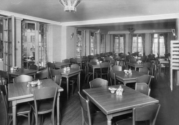 Dining room of Tatham House YWCA. A horse-drawn vehicle and an automobile can be seen through the window.
