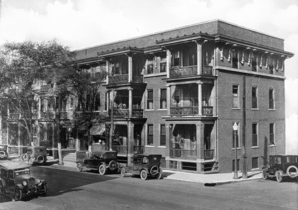A view of the Hotel Martinque. Cars are parked on the street near the hotel, which is a three-story brick building with balconies.