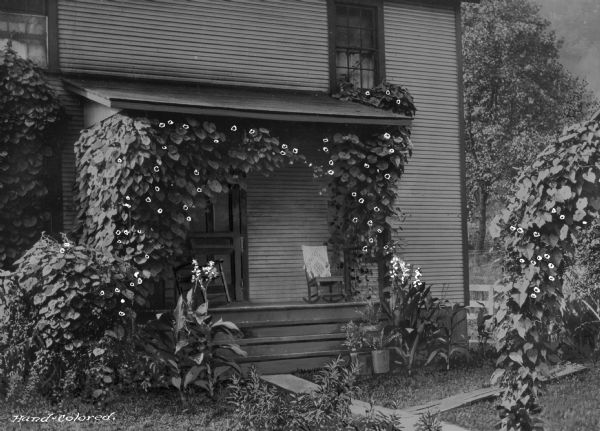 View of the front of a home, porch and yard in a company town of Consolidated Coal Company.  An archway covered with ivy is in front of the home.