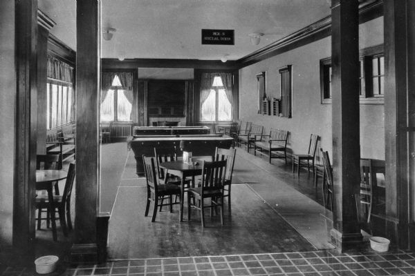 View of men's recreation room in the community recreation hall. Room features pool tables, tables and chairs and a fireplace. Sign reads: "Men's Social Room." Lindale was a company town of Pepperell Manufacturing Company.