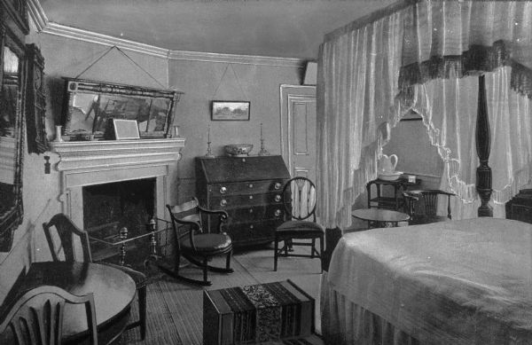 View of Nellie Custis' bedroom in Mount Vernon, the residence of George Washington. Nellie Custis, the granddaughter of Martha Washington and step-granddaughter of George Washington, was raised at Mount Vernon by her grandparents after her father died in 1781. The room features a canopy bed, fireplace, chairs and tables, desk, a clock and artwork.