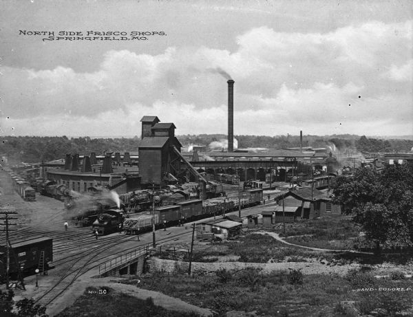 Elevated view of the St. Louis and San Francisco railroad shops. View of train yard where many trains and cars are parked. Caption at top left reads: "North Side Frisco Shops, Springfield, Mo."