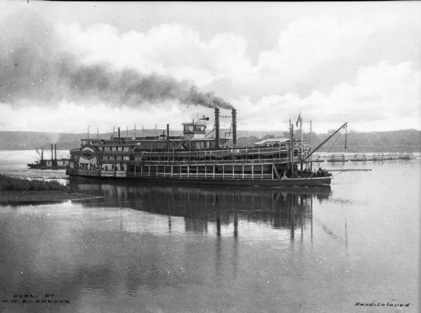 View of the steamboat "St. Paul" in the Mississippi River near Sabula. Signs painted on the ship read: "St. Louis Dubuque, St. Paul Streckfus Steamers Saint Paul." A smaller boat is in the background.