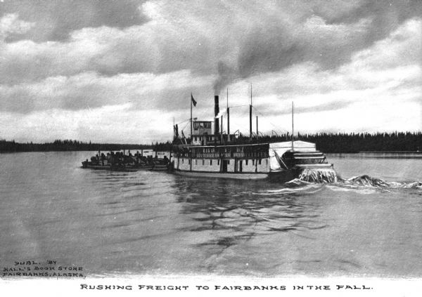 View of a steamboat transporting freight to Fairbanks. Text on photograph reads: "Rushing Freight To Fairbanks In The Fall."