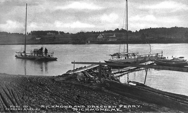 View of the Richmond and Dresden ferry in the Kennebec River, about to land. A man and a horse with cart are on the ferry. Several canoes and a sailboat is docked nearby. Caption reads: "Richmond And Dresden Ferry, Richmond, Me."