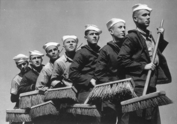 Seven sailors pose with their brooms at the U.S. Coast Guard training station.