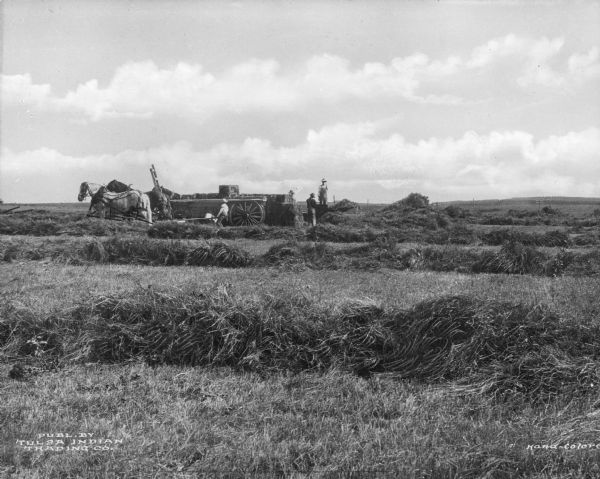 Several agricultural workers are shown baling hay in the vicinity of Tulsa.