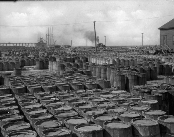 Elevated view of barrels outdoors in naval storage. A truck is in the far background.