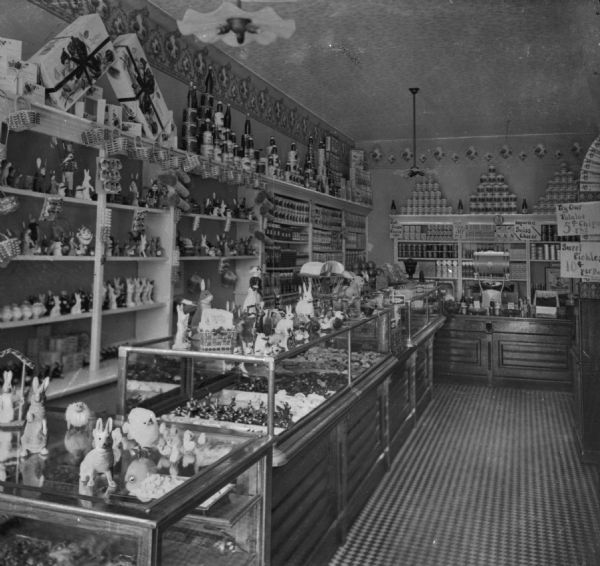 Interior of a general store. Toys, porcelain animals, canned goods, and bottles line the store shelves.