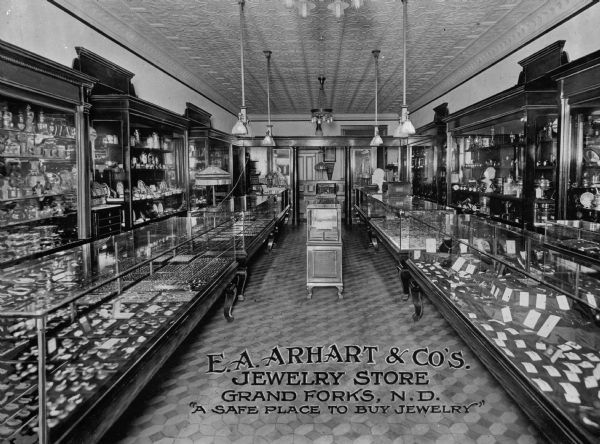 Interior view of "E.A. Arhart & Co's. Jewelry Store" with display cases full of items for sale. Additional text reads, "A Safe Place to Buy Jewelry."