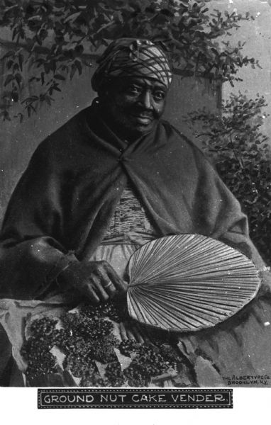 An elderly African-American woman posed seated holding a fan in her right hand. Text underneath the image reads "Ground Nut Cake Vendors."