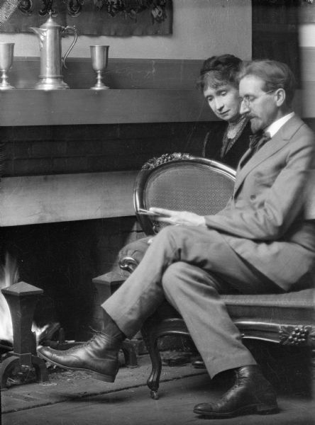 Ephraim Burt Trimpey and his wife Alice Kent Trimpey sit in front of their fireplace. The Trimpeys were antique dealers and collectors; Mr. Trimpey was also a professional photographer.