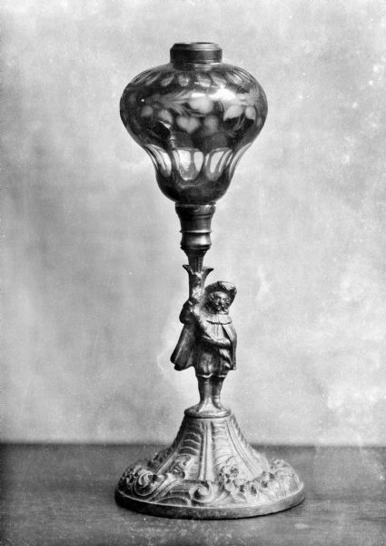 An old oil lamp with a cut cased glass font and a cast metal base in the form of a cavalier.