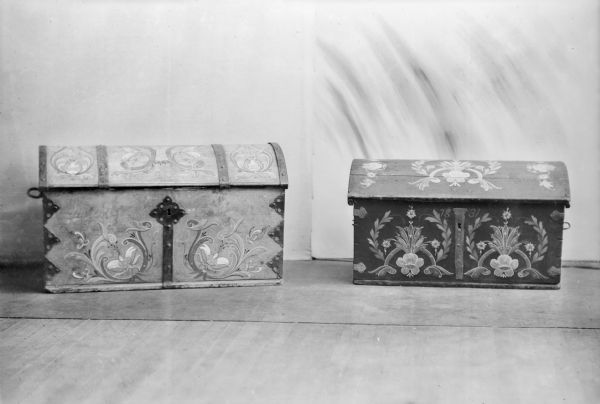 Two Scandinavian chests with handmade metal fittings and decorative rosemaling. The chest on the right is dated 1831.