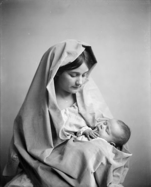 A studio portrait of a veiled woman and sleeping infant.