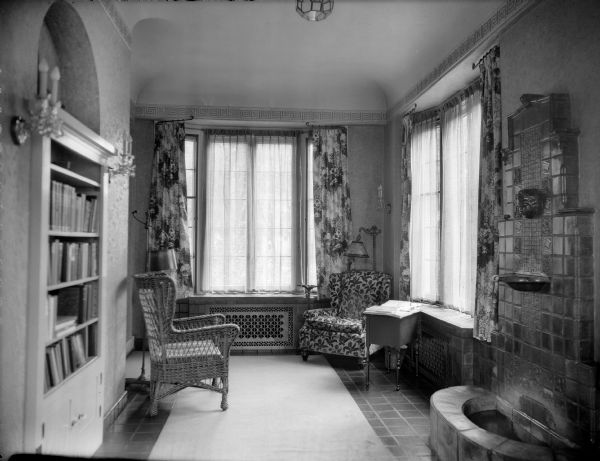 Interior view of the home of William Llewellyn and Zona Gale Breese, showing a wall fountain and wicker chair. There is extensive use of Arts and Crafts-style tile in the room on the floor, fountain, and window seats, which serve as radiator covers.