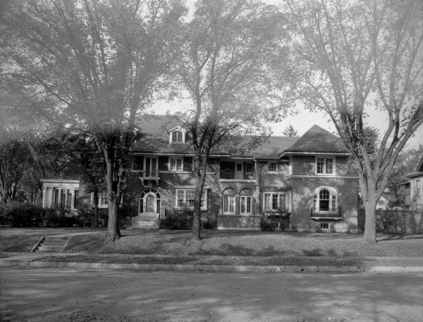 An exterior view of the home of William Llewellyn and Zona Gale Breese. The brick and stucco house has features of several styles. The original 1912 structure, to the left, is Georgian Revival, whereas the large 1928 addition on the right has elements of the Mediterranean Revival style.