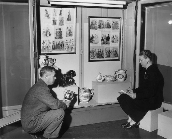 John Jenkins, museum director, and Ruth K. Harris, museum curator, of the (then) State Historical Society of Wisconsin museum prepare a display case for an exhibit of English lusterware. The collection was bequeathed to the society by Ephraim Burt Trimpey of Baraboo.