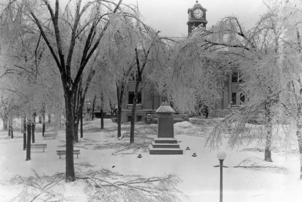 Limbs litter the ground under trees heavily coated with ice on the Sauk County Courthouse Square after an ice storm.