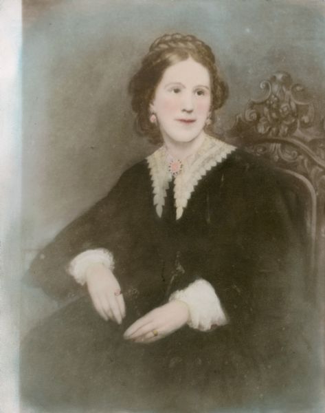 Hand-colored waist-up portrait of Alice Kent Trimpey, seated on a chair with an elaborately carved back. She is wearing nineteenth-century clothing consisting of a dark dress with lace collar and cuffs. A brooch secures the collar. She is wearing earrings, and has a braid wrapped on top of her head. This is a photographic copy of an older photograph or drawing.