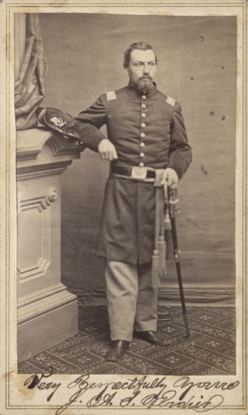 Full-length carte-de-visite portrait of John A.S. Verdier from Company H of the 27th Wisconsin Infantry. He is standing in full uniform resting his right elbow on a column, and holding the pommel of his sword in his left hand.