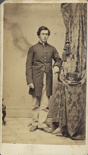 Full-length carte-de-viste portrait of Edward Savage of Company B from the 28th Wisconsin Infantry standing near a curtain.