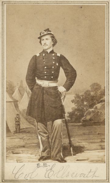 Carte-de-visite featuring a full-length hand-drawn portrait of Colonel Elmer E. Ellsworth, F & S, 11th New York Infantry in full Union uniform, leaning on his sword. He was born in Malta, New York, but moved to Chicago, where he worked as a law clerk. He was also close to President Lincoln and his family. He was killed on May 24, 1861 in Alexandria, Virginia, while he and a few others went to remove a Confederate flag. He was succeeded by Lieutenant Colonel Farnham.