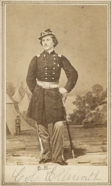 Carte-de-visite featuring a full-length hand-drawn portrait of Colonel Elmer E. Ellsworth, F & S, 11th New York Infantry in full Union uniform, leaning on his sword. He was born in Malta, New York, but moved to Chicago, where he worked as a law clerk. He was also close to President Lincoln and his family. He was killed on May 24, 1861 in Alexandria, Virginia, while he and a few others went to remove a Confederate flag. He was succeeded by Lieutenant Colonel Farnham.
