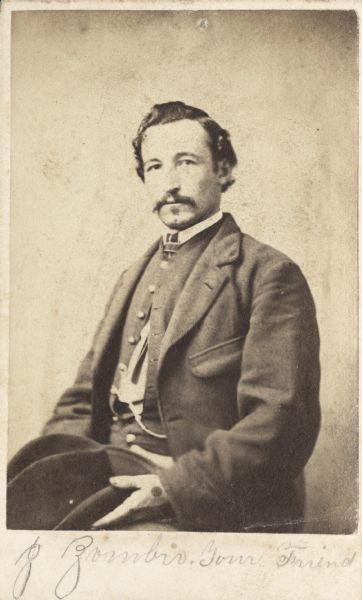 Waist-up carte-de-visite portrait of John A. Zombro, Company D, 107th Illinois Infantry, out of uniform with his hat on his lap.  When he was mustered into service he held the rank of private, and when he was mustered out he was a sergeant.