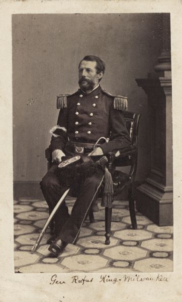 Seated carte-de-visite portrait of General Rufus King in uniform with epaulettes, with a sword across his left leg.