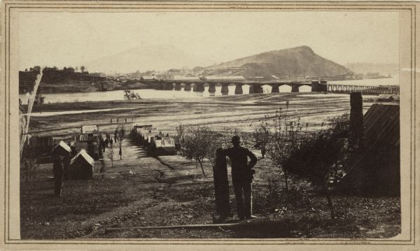 View across the Tennessee River toward the city and Cameron Hill, showing the military bridge and some Union Army installations put up following the occupation of Chattanooga in September, 1863. The bridge was destroyed in the flood of 1867, but a pier was still visible and pointed out to visitors late in the century. The site was heavily fortified. There are many published accounts of the military engagements here.