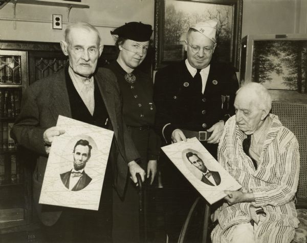Two unidentified Civil War veterans at soldier's home on December 23, 1938, along with two representatives from the American Legion. The veterans are both holding portraits of Abraham Lincoln.