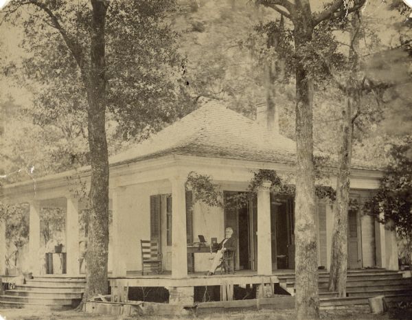 Jefferson Davis sitting in a chair on the porch of his residence.