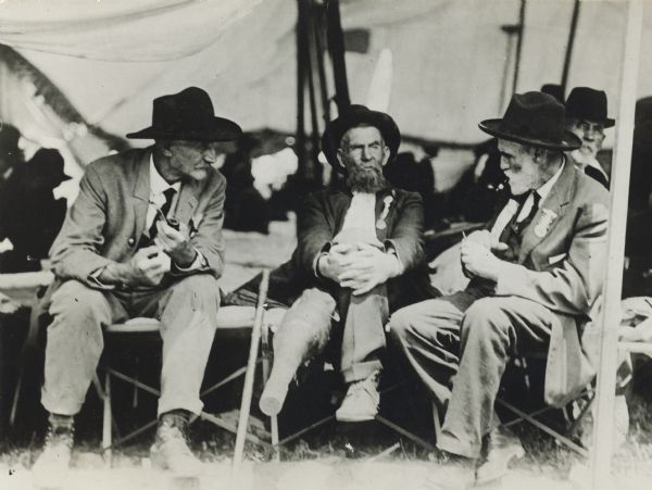 Three Confederate veterans sitting in a tent at the National Confederate Reunion.