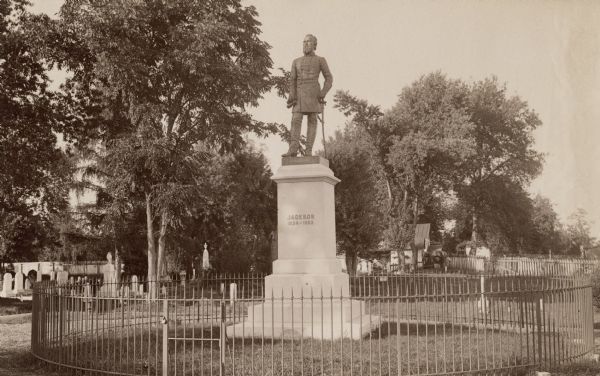 A monument and statue honoring the Confederate general Thomas Jonathan "Stonewall" Jackson. There is a cemetery in the background on the left.