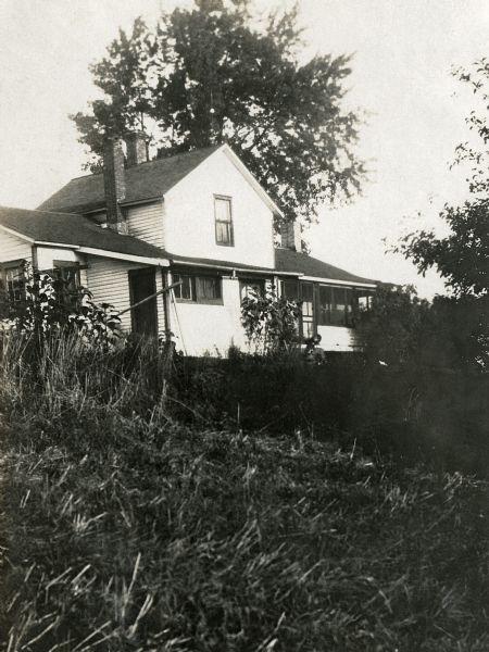 View of the Quinney family's farmhouse including screened porch and yard.