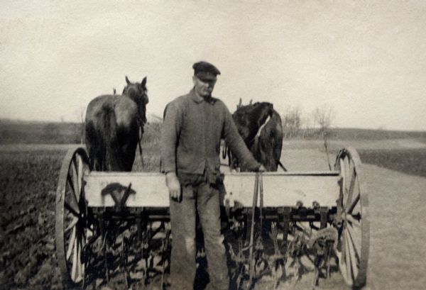 John Quinney, Richard Quinney's grandfather, standing in front of a horse-drawn harrow on the fields of his farm.