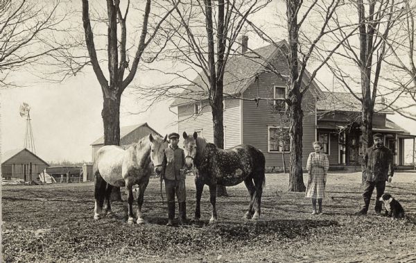 Marjorie Quinney and Henry and Howard Reynolds stand in front of the Reynold's family farmhouse with two horses and a dog.