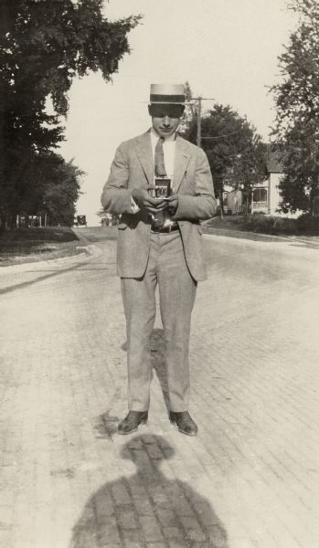 Floyd Quinney focusing his Kodak Autographic on a suburban street.